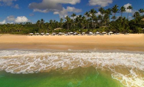a beach with chairs and umbrellas and the ocean at Rio Da Barra Villa Hotel in Trancoso