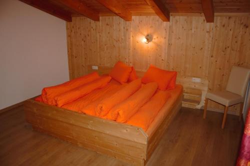レンゲンフェルトにあるAppartement Anitaの木製ベッド1台(オレンジのシーツ付)