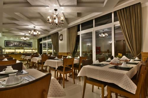 a restaurant with tables and chairs and a chandelier at Micheline Hotel Tricot - ao lado da Rua Coberta in Gramado