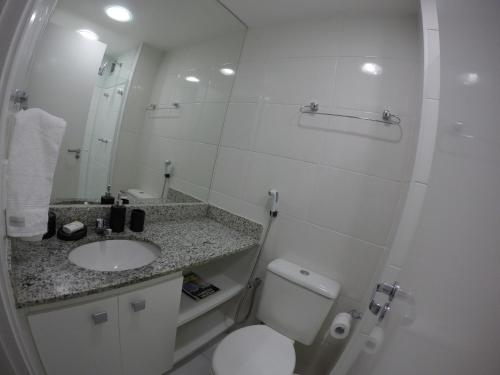 a bathroom with a toilet and a sink and a mirror at Apartamento Porto Real Suítes in Mangaratiba