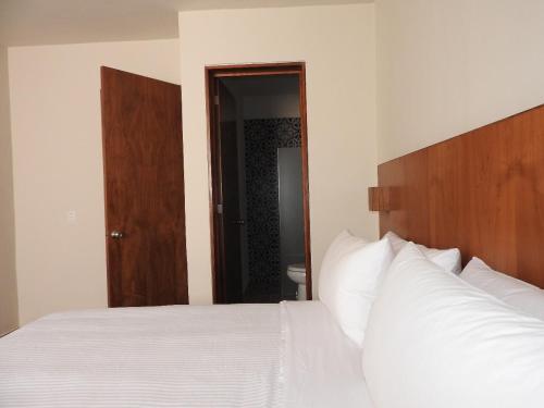 a bedroom with a white bed with a wooden headboard at Villas La Ceiba in Playa del Carmen