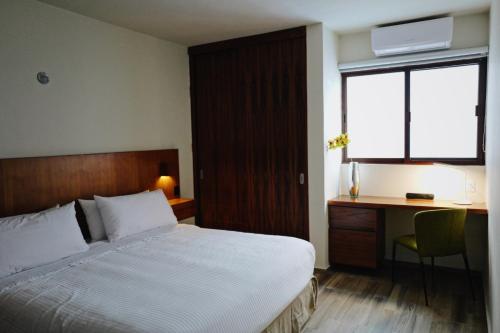 a bedroom with a bed and a desk and a window at Villas La Ceiba in Playa del Carmen