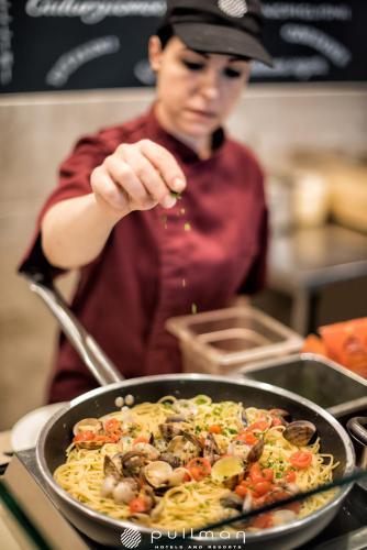 a woman pointing at a pan of pasta with mushrooms at Almar Timi Ama Resort & Spa in Villasimius