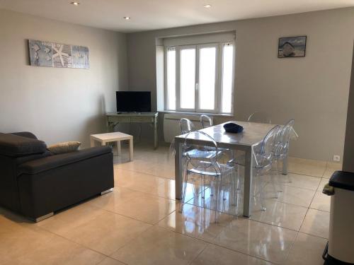 un salon avec une table, des chaises et un canapé dans l'établissement La Plage d'Or, à Vierville-sur-Mer