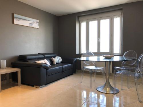 a living room with a black couch and a table at La Plage d'Or in Vierville-sur-Mer