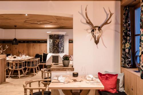 a restaurant with a table with a deer head on the wall at Relais & Châteaux Gut Steinbach Hotel Chalets SPA in Reit im Winkl