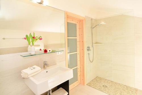 y baño blanco con lavabo y ducha. en Hotel Verena en Lana