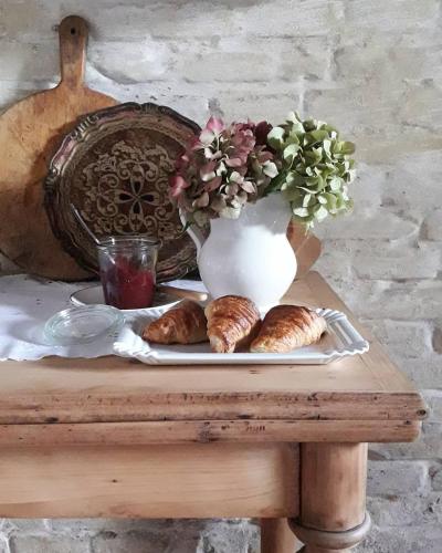 a table with a plate of pastries and a vase at Piccola Corte Antica in Corticelle Pieve