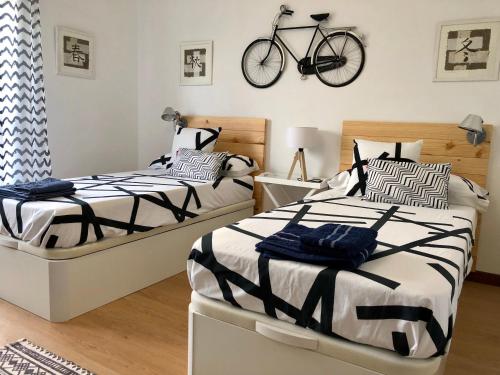 2 Betten in einem Schlafzimmer mit einem an der Wand hängenden Fahrrad in der Unterkunft La Campa 7.2 in Logroño
