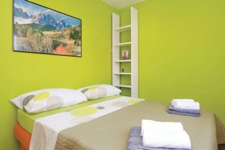 a green bedroom with a large bed with two pillows at Mirta in Kastel Novi