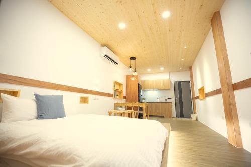 a bedroom with a large white bed and a kitchen at Lost Circle Homestay in Tainan