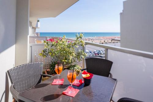 a table with wine glasses on a balcony with the beach at Hotel Ambassador in Bibione