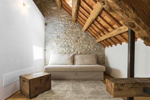 a couch in a room with a stone wall at Relais Poggio Pagnan in Farra