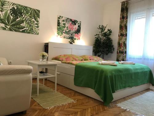 a bedroom with a bed with a green blanket on it at Rosmarinus Apartman in Pécs