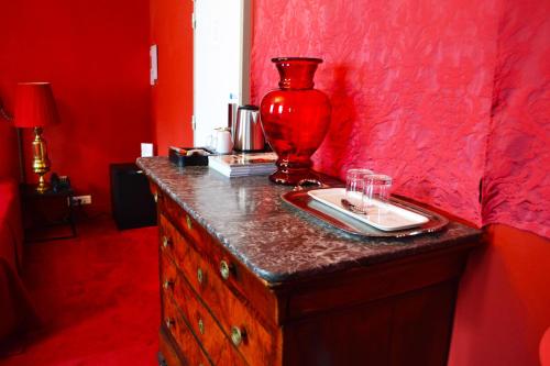 una habitación roja con un jarrón en una cómoda con gafas en Hotel Windsor Home, en París