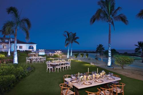 a table set up for a wedding on a lawn with palm trees at Secrets Puerto Los Cabos Golf & Spa18+ in San José del Cabo