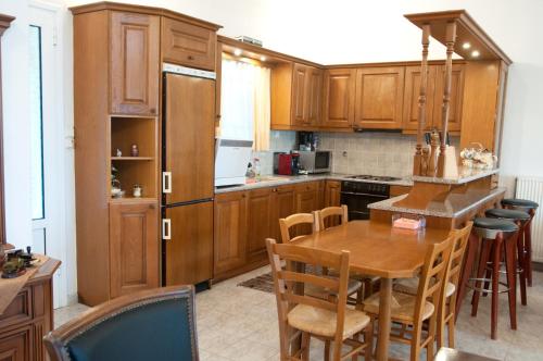 una cocina con armarios de madera y una mesa con sillas. en Oasis Olympia Apartments en Smíla