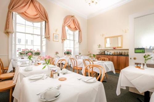 a restaurant with white tables and chairs and windows at Edgar Townhouse in Bath