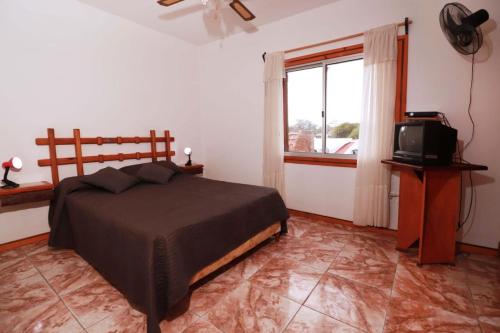 1 dormitorio con 1 cama, TV y ventana en Apartamentos lo de Renan, en La Paloma