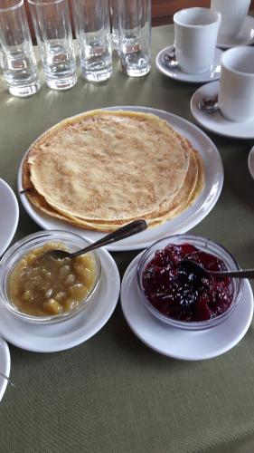 a table with plates of food with pancakes and jam at Jaun-Ieviņas in Rauna