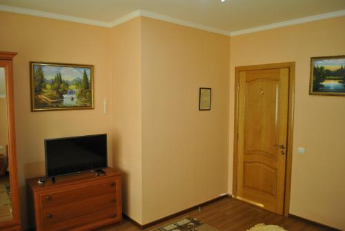 a living room with a television on a dresser and a door at Квітковий двір in Golubinoye