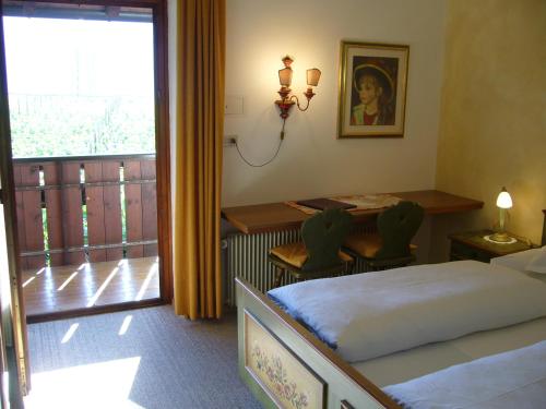 Schlafzimmer mit einem Bett, einem Tisch und einem Fenster in der Unterkunft Hotel Gasthof WASTL in Appiano sulla Strada del Vino