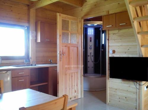 a kitchen with a shower in a log cabin at Rega domki in Sarbinowo