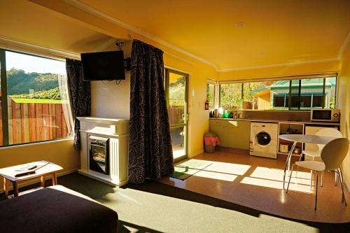a yellow living room with a fireplace and a table at Bay Cottages in Kaikoura