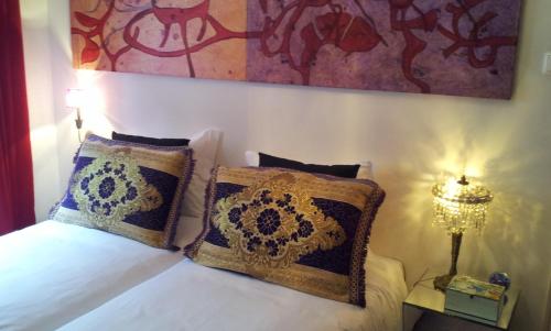 a bedroom with a bed with two pillows and a painting at Whatever Art B&B in Lisbon