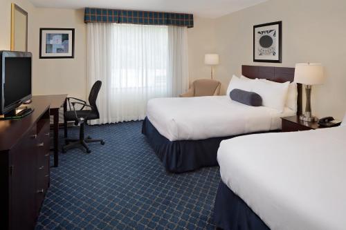 a hotel room with two beds and a desk and a tv at Boxboro Regency in Boxborough