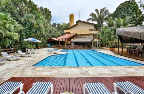 a pool at a resort with chairs and a building at Flat Amarilis und 110 Riviera de Sao Lourenco SP in Riviera de São Lourenço