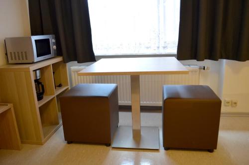 a kitchen with a table and two stools and a microwave at Hana Aparthotel in Hamburg