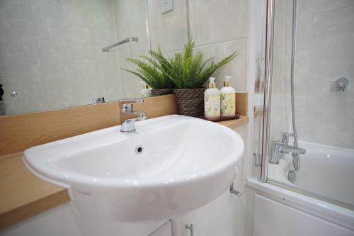 a white sink in a bathroom with a shower at London Excel - O2 Arena - London City Airport Superior Apartment in London