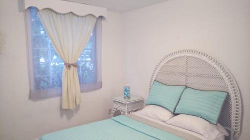a bedroom with a white bed with a window at Departamento Tucán in Cancún