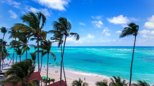 a view of a beach with palm trees and the ocean at Hotel Checkin El Cortecito Beach in Punta Cana