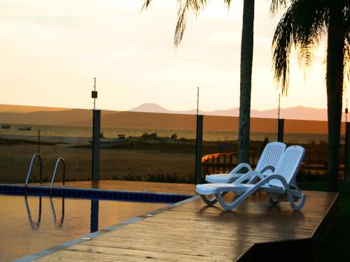 2 chaises assises sur un quai à côté d'une piscine dans l'établissement Posada Sueños De Verano, à Florianópolis