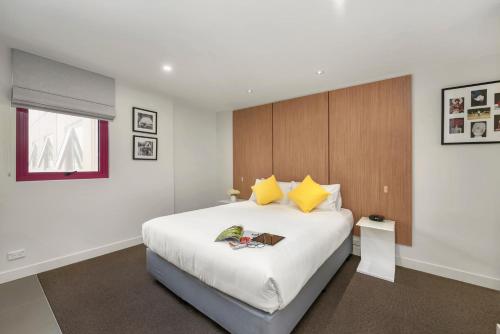 ein Schlafzimmer mit einem großen weißen Bett und einem Fenster in der Unterkunft Plum Serviced Apartments Carlton in Melbourne