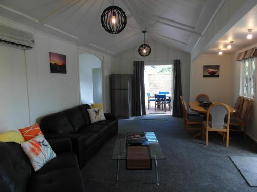 a living room with a black couch and a table at Cottages On St Andrews in Havelock North