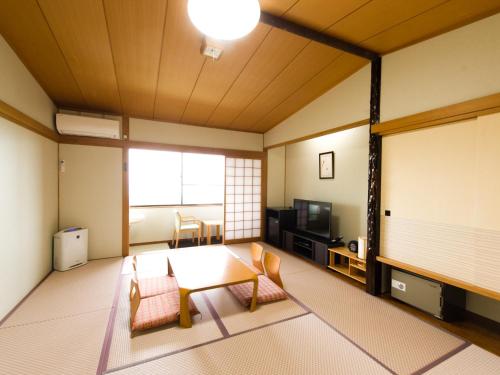a room with a table and chairs and a tv at LiVEMAX RESORT izukogen in Ito