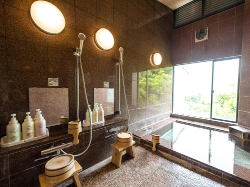 a bathroom with a tub and a shower and a sink at LiVEMAX RESORT izukogen in Ito