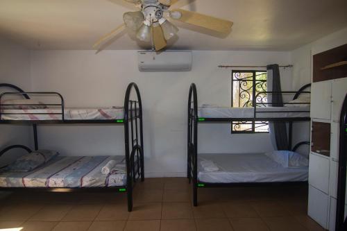 a room with three bunk beds and a ceiling fan at Wipeout Hostel in Jacó