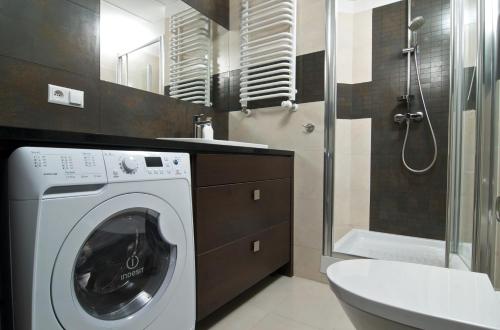 a washing machine in a bathroom with a shower at Silver Apartments in Wrocław
