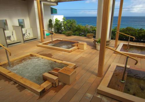 a room with a hot tub with the ocean in the background at Atagawa Yamatokan in Higashiizu