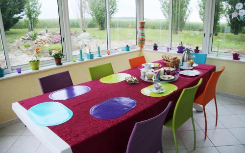 uma mesa de jantar com uma toalha de mesa vermelha e cadeiras coloridas em Domaine de la Pendule em Issel