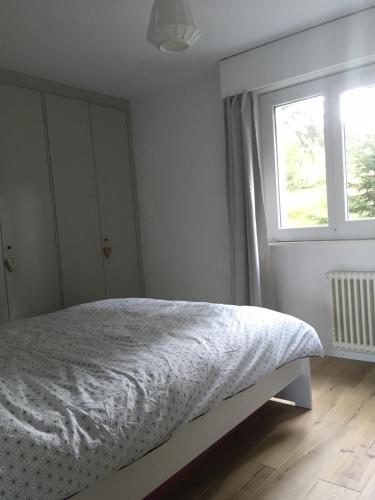 a white bedroom with a bed and a window at Choucas A in Crans-Montana
