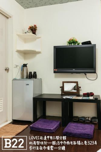 a room with a table and a television on a wall at Fengjia Love I Hostel in Taichung