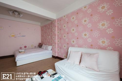 a bedroom with two beds and pink flowers on the wall at Fengjia Love I Hostel in Taichung