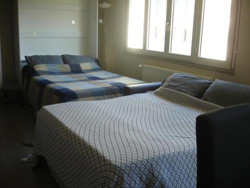 バイヨンヌにあるStudio Centre Ville Office De Tourismeのベッド2台、ソファ、窓が備わる客室です。