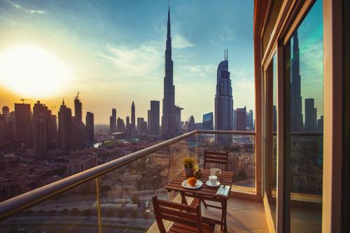 a person sitting at a table in front of a city at Boutique Living - Burj Views Downtown Dubai in Dubai