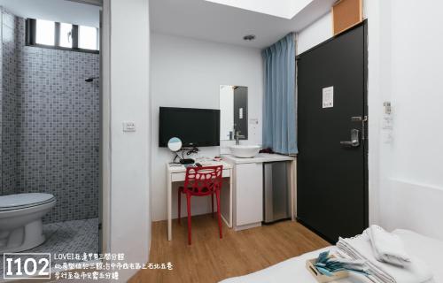 a bathroom with a toilet and a desk with a sink at Fengjia Love I Hostel in Taichung